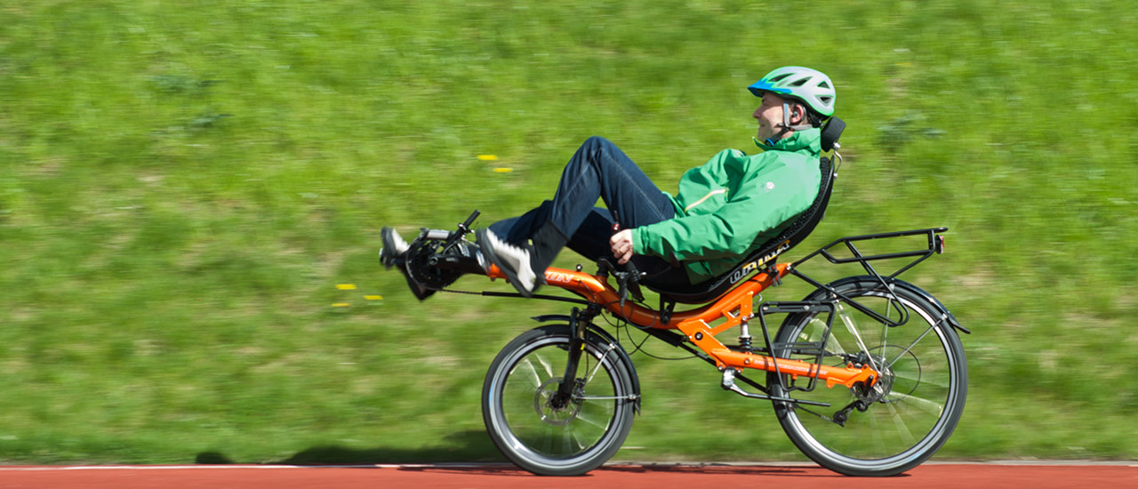 Peter på sin orange liggecykel med grønne omgivelser i baggrunden